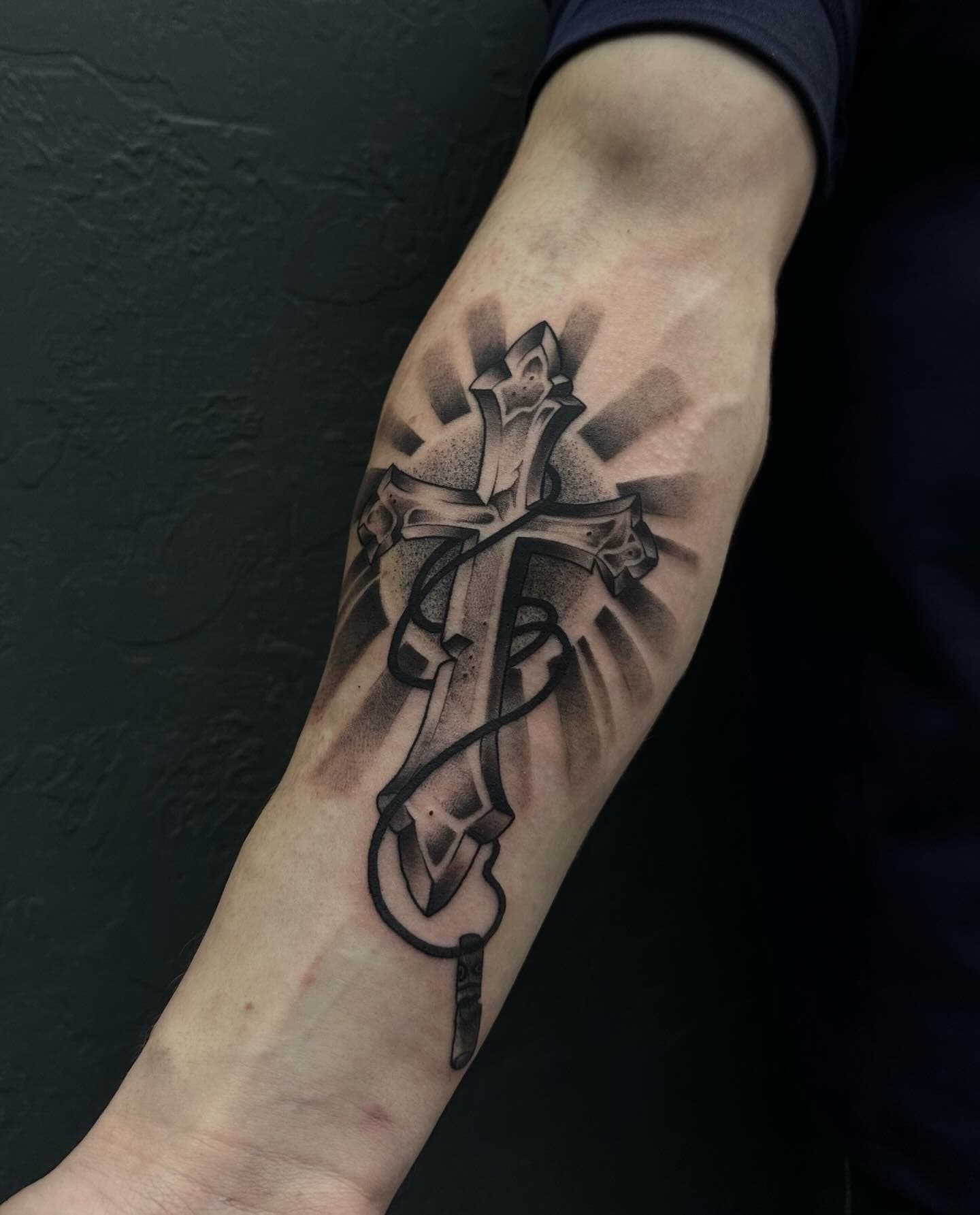 Healed black and grey cross tattoo on the forearm, made at LUX INK in Batumi
