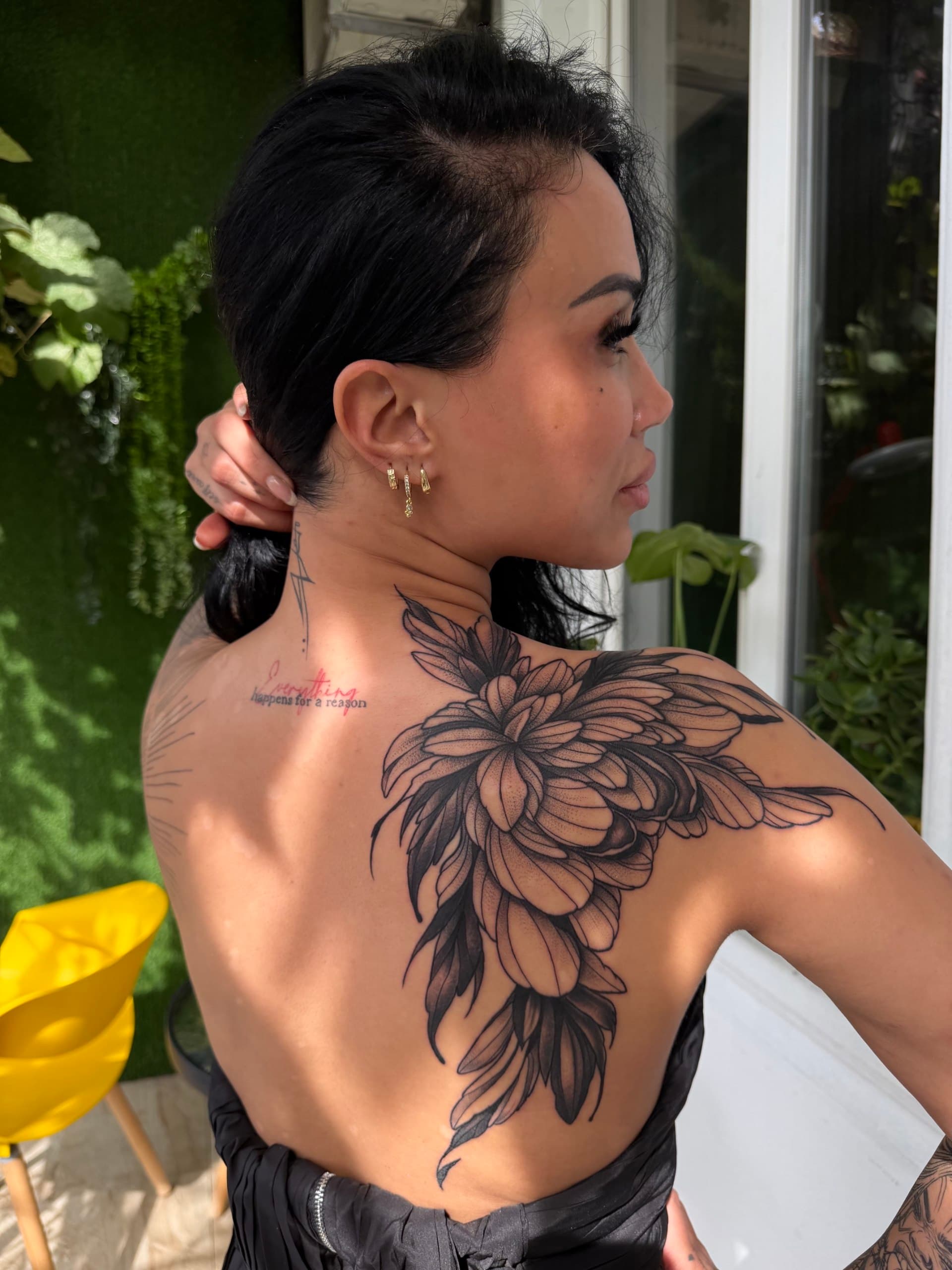 Floral dotwork tattoo on the shoulder and back, photographed in the sun in Batumi
