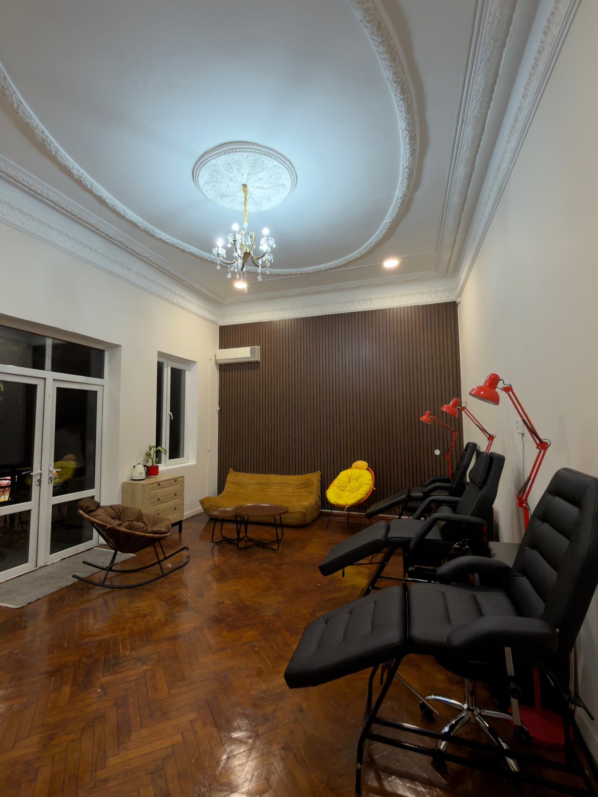 Interior of LUX INK tattoo studio in Batumi with classic stucco ceiling and crystal chandelier